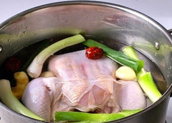  Cho gà vừa mới rửa sạch vào nồi nấu phở thêm một số nguyên liệu khác như hành, ngò rí, gừng. 
